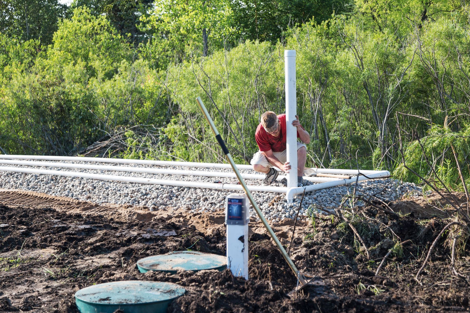 Person in a red shirt working beside a railroad track in a wooded area
