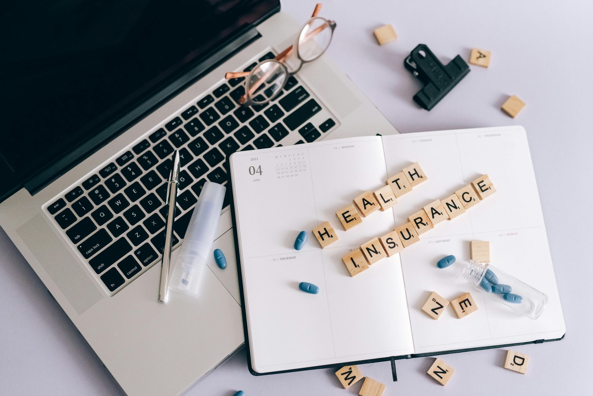 A laptop is sitting on top of a notebook with the words health insurance written on it.