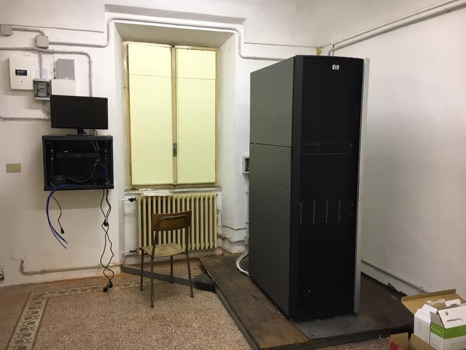 Grande rack server nero in una stanza accanto a una finestra, con un monitor e una sedia.