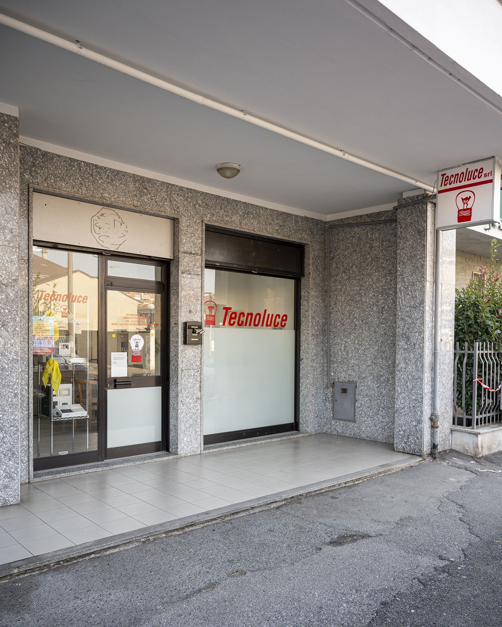 Esterno dell'ufficio immobiliare Tecnocasa con porte in vetro e logo rosso.