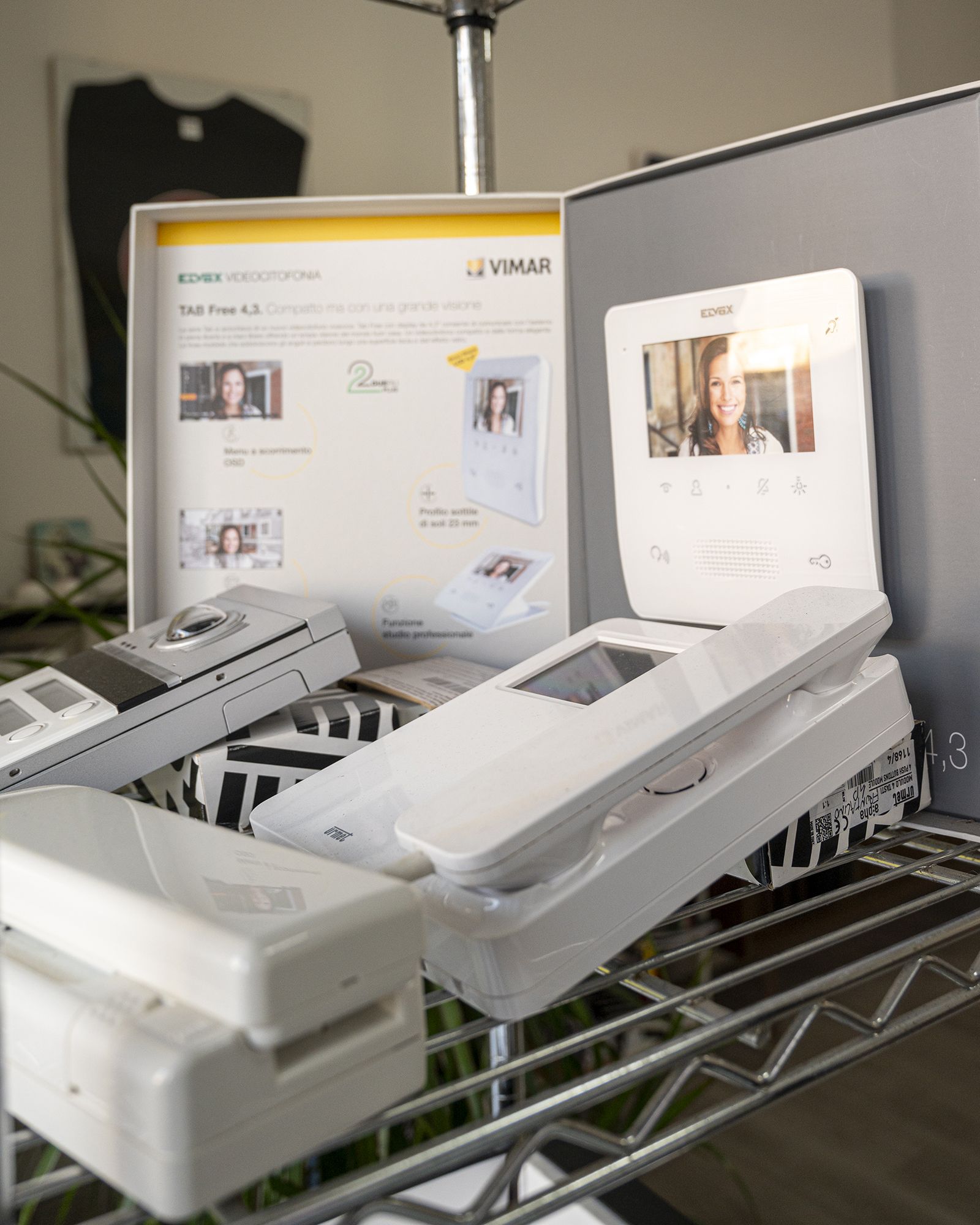 Componenti bianchi del sistema di interfono su uno scaffale, tra cui un monitor, una stazione porta e stazioni base.