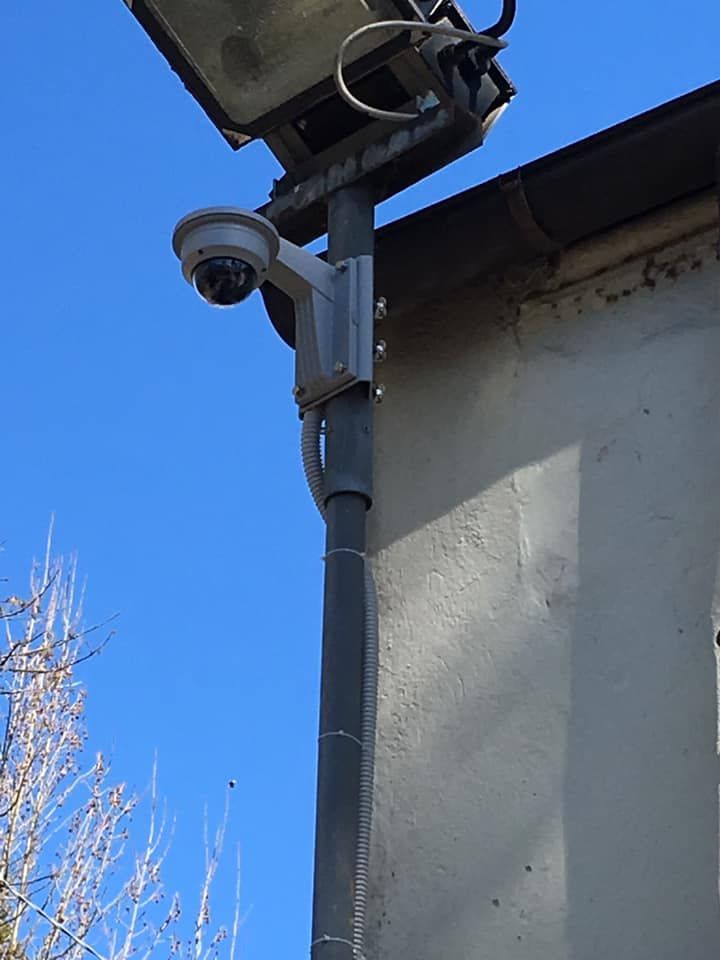 Telecamera di sicurezza montata su un palo accanto a un edificio, con un pannello solare sopra.