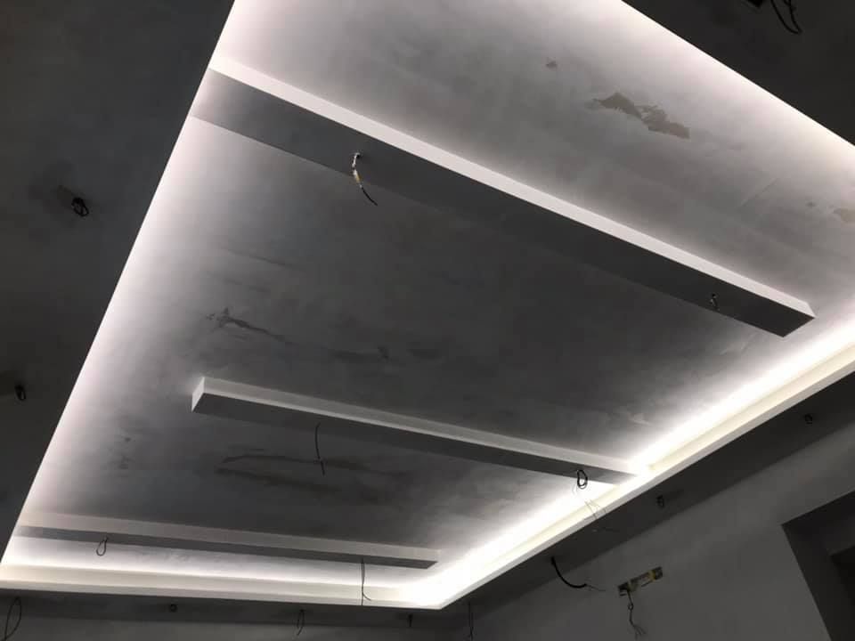 Soffitto con strisce luminose incassate. Cablaggio a vista. Superficie in cemento.