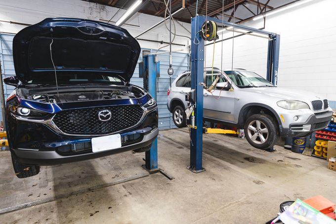 Two cars on lifts in a garage | MasterTech Auto Care