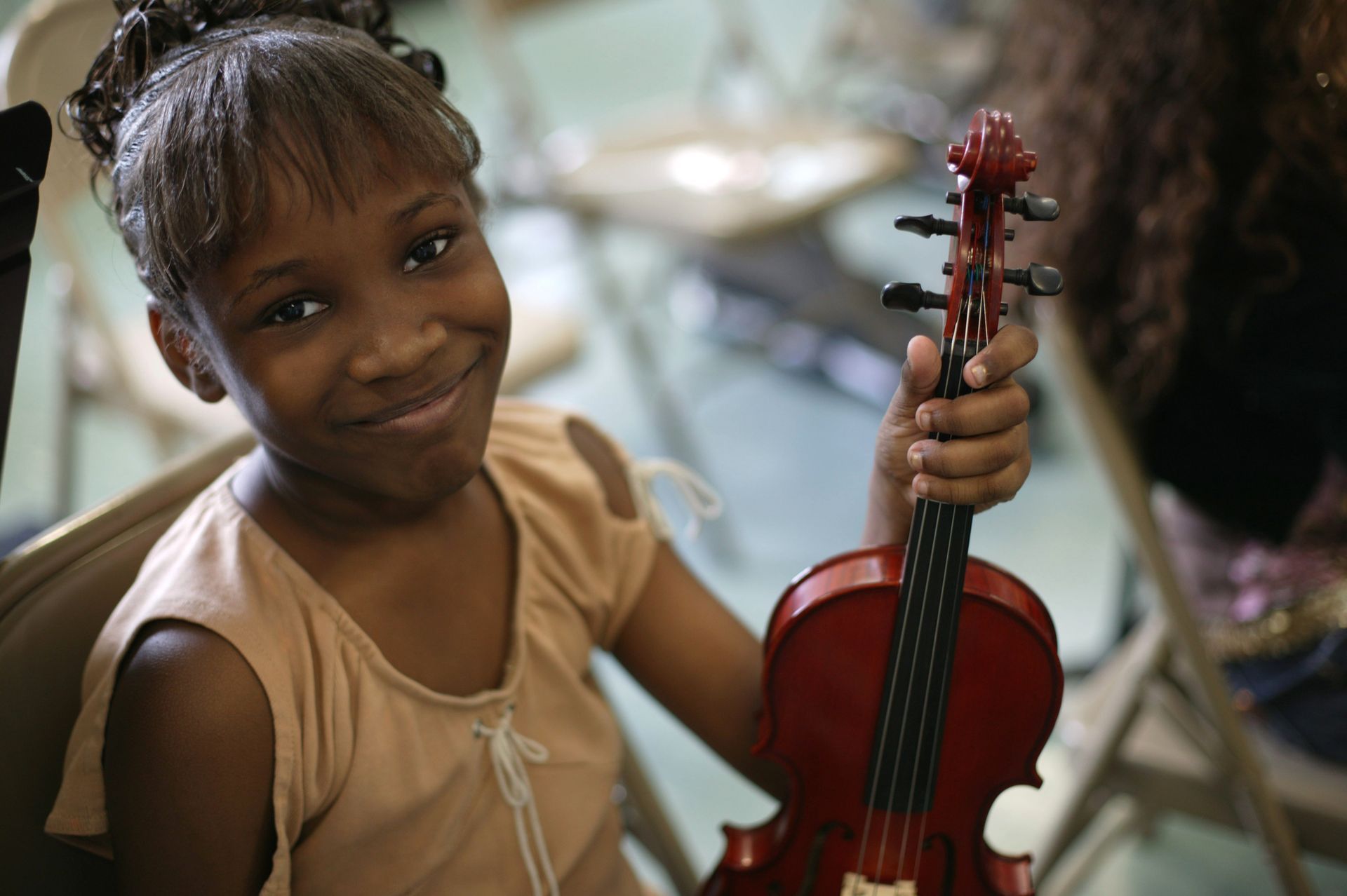 A young girl is holding a violin and smiling A young girl is holding a violin and smiling