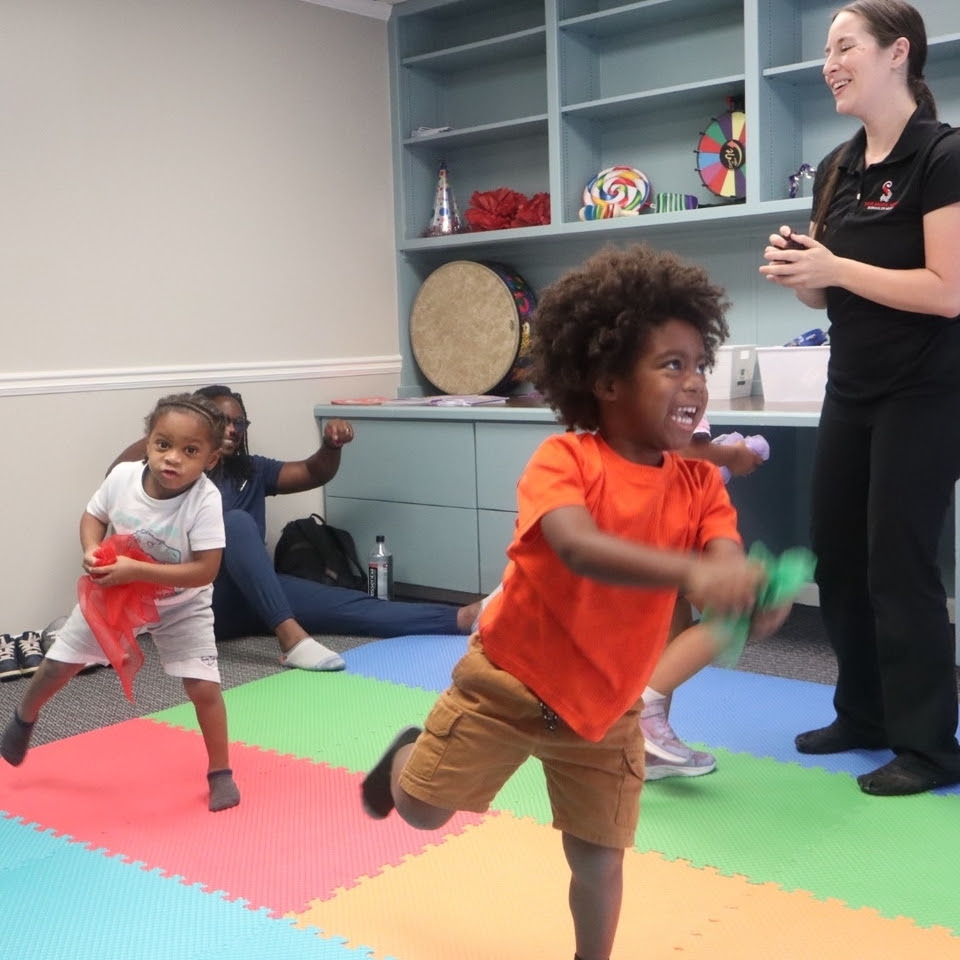 Children playing in a colorful room with an adult. The children hold colorful streamers and weights, the adult smiles. Children playing in a colorful room with an adult. The children hold colorful streamers and weights, the adult smiles.