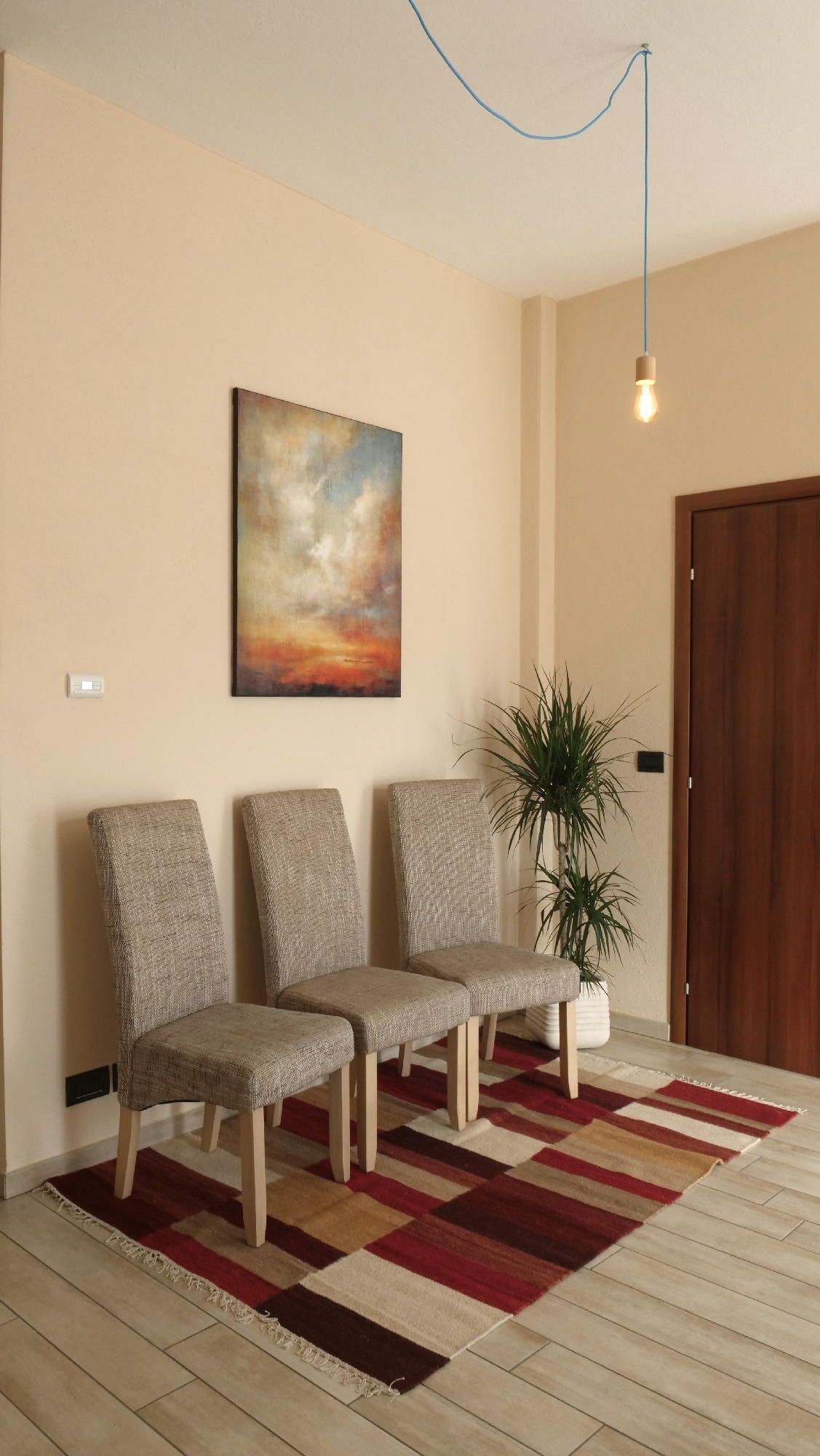 Una sala d'attesa con sedie, un tappeto e un quadro sul muro.