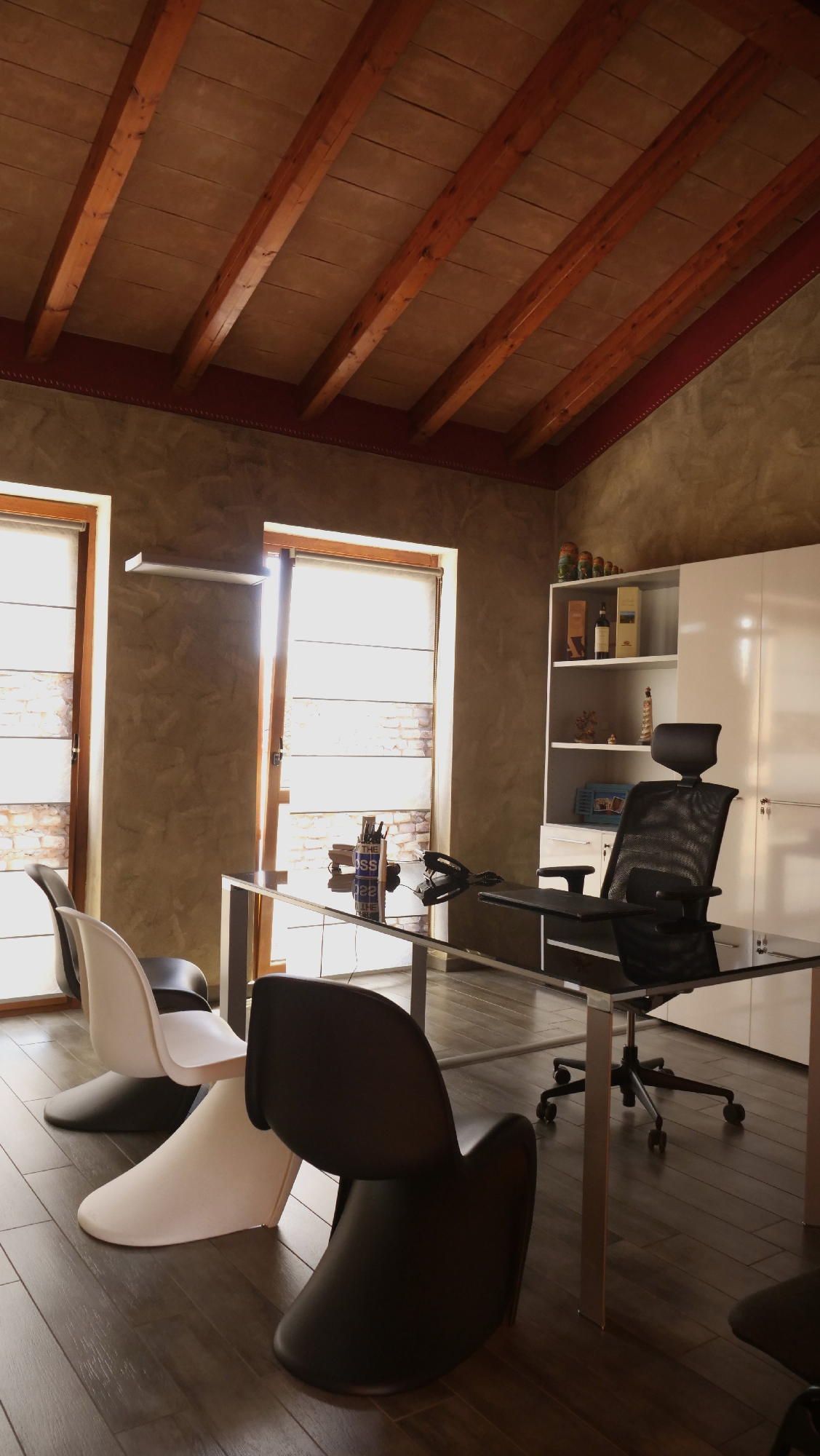 Una stanza con una scrivania e sedie e un soffitto in legno