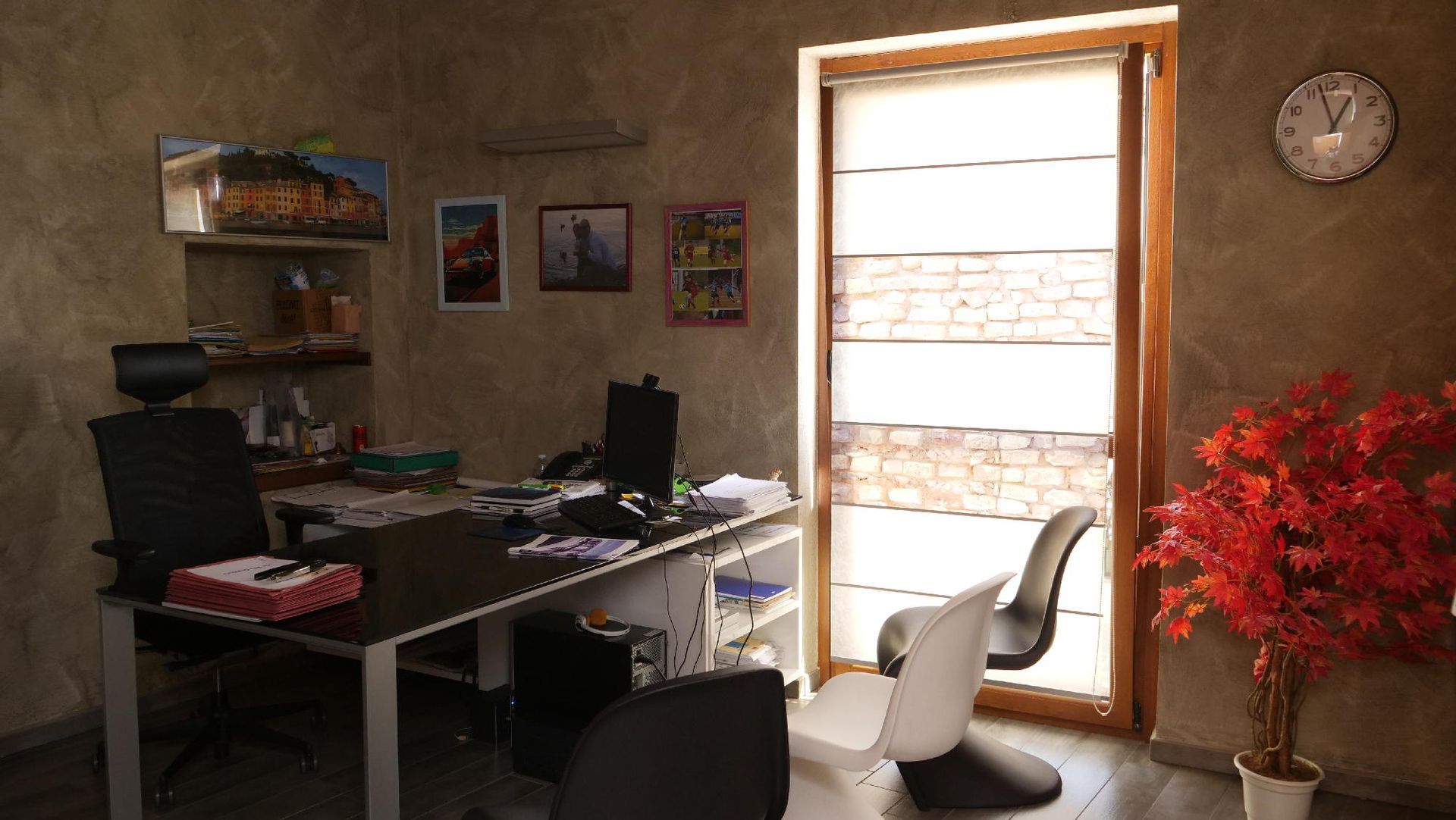 Un ufficio con una scrivania e delle sedie e un orologio sul muro