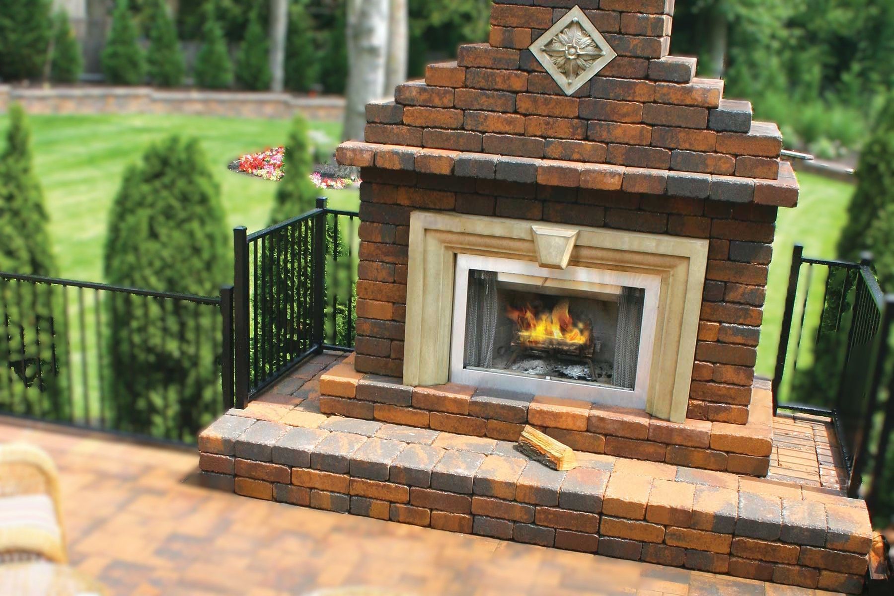 Brick outdoor fireplace with flames on a patio.
