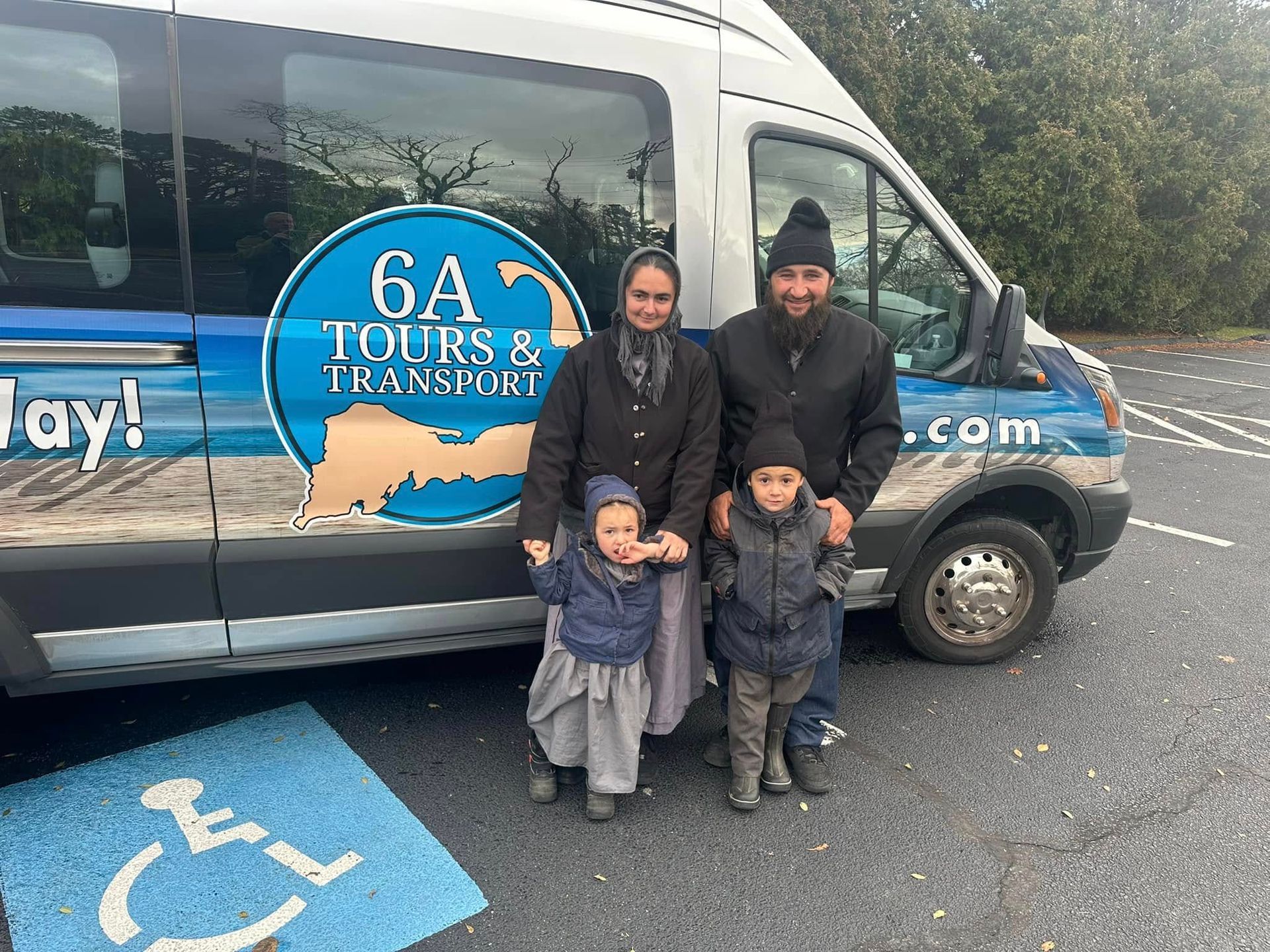 A family stands in front of a 6A Tours & Transport van parked in a handicap-accessible parking space.