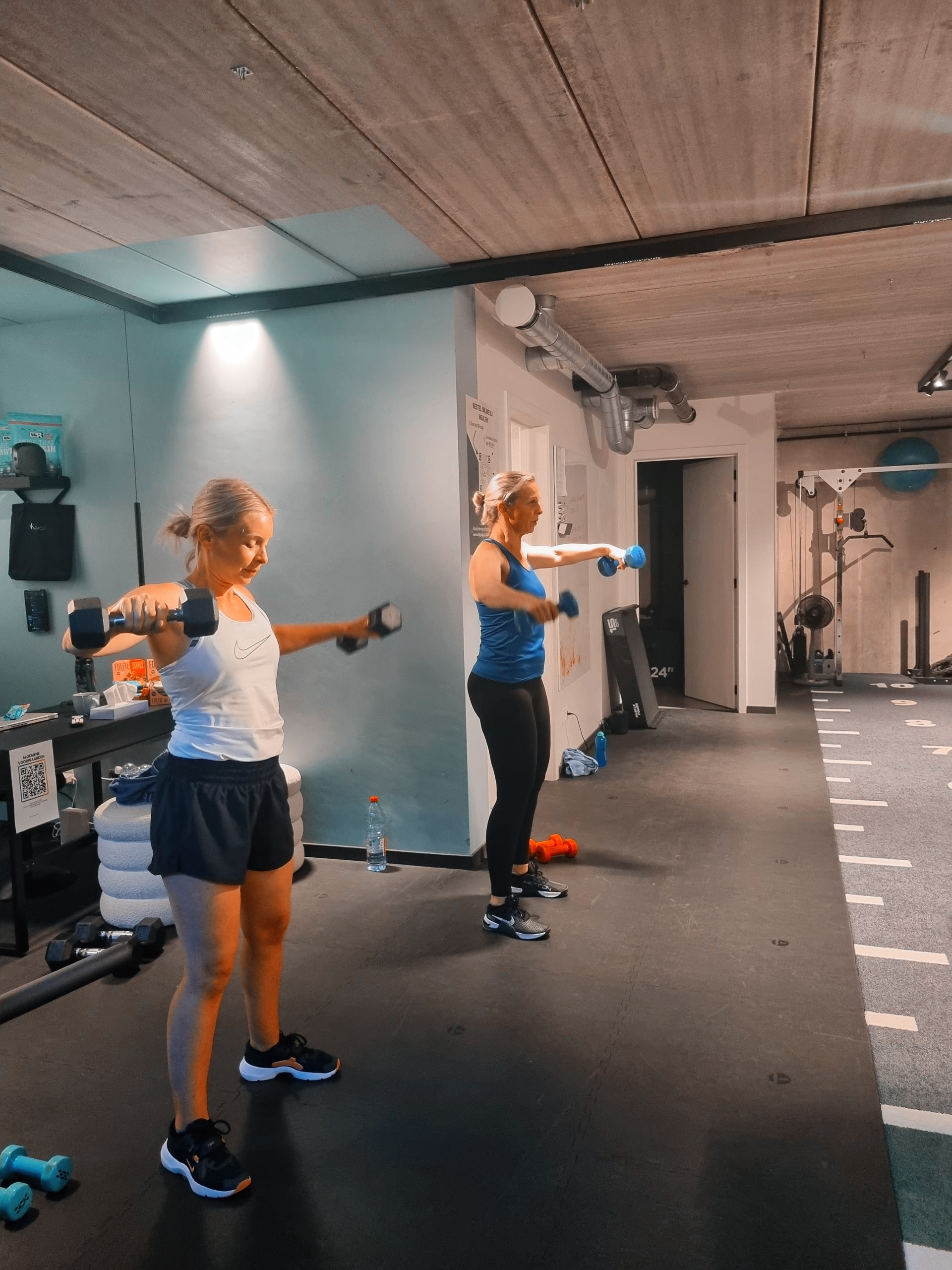 Twee mensen doen armoefeningen met weerstandsbanden in een fitnessstudio.