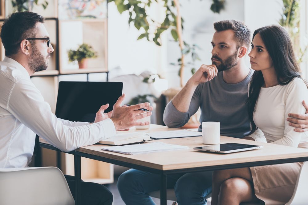 A Man is Talking to a Couple Sitting at a Table — MoneySmith Group In Kingscliff, NSW