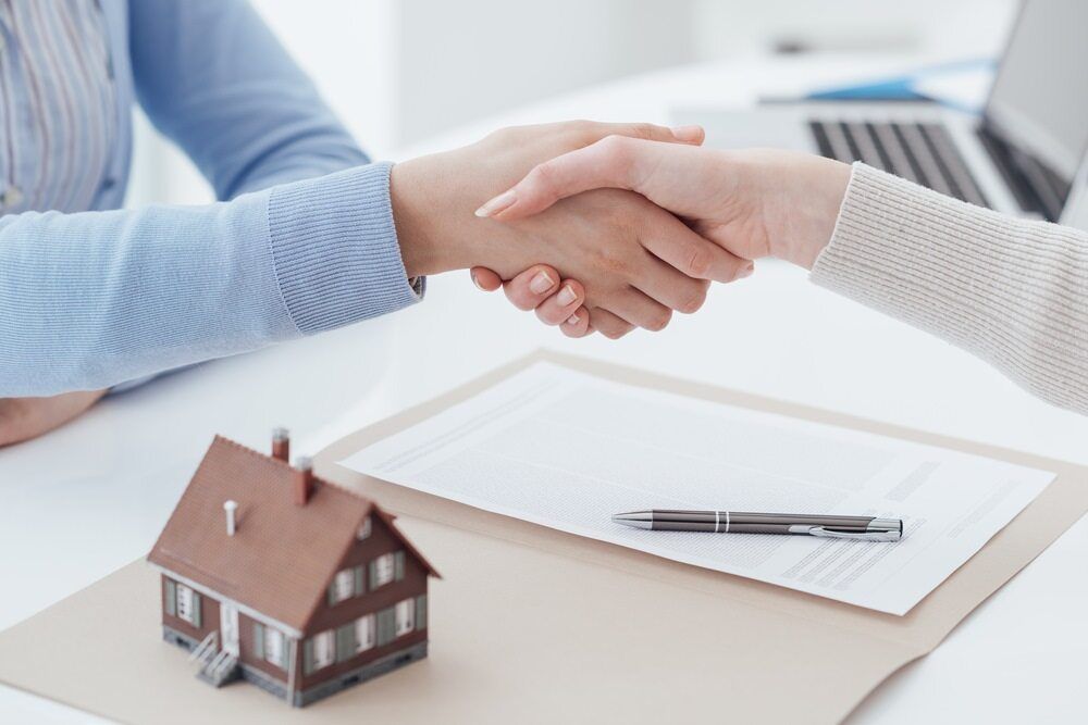 Two People Are Shaking Hands Over a Piece of Paper — MoneySmith Group In Kingscliff, NSW
