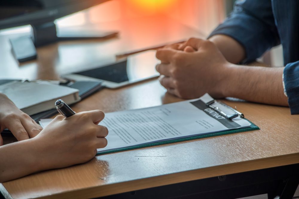 A Man and a Woman Are Sitting at a Table Signing a Document — MoneySmith Group In Kingscliff, NSW