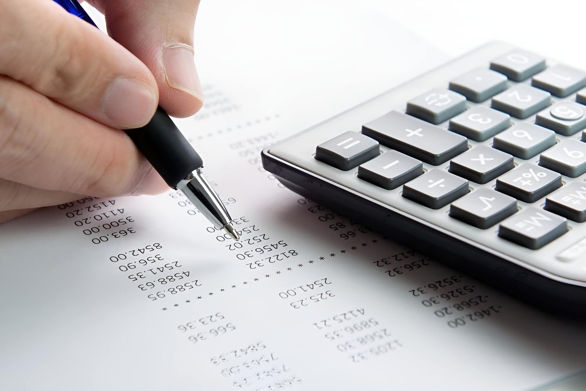 A Person is Writing on a Piece of Paper Next to a Calculator — MoneySmith Group In Coolangatta, QLD