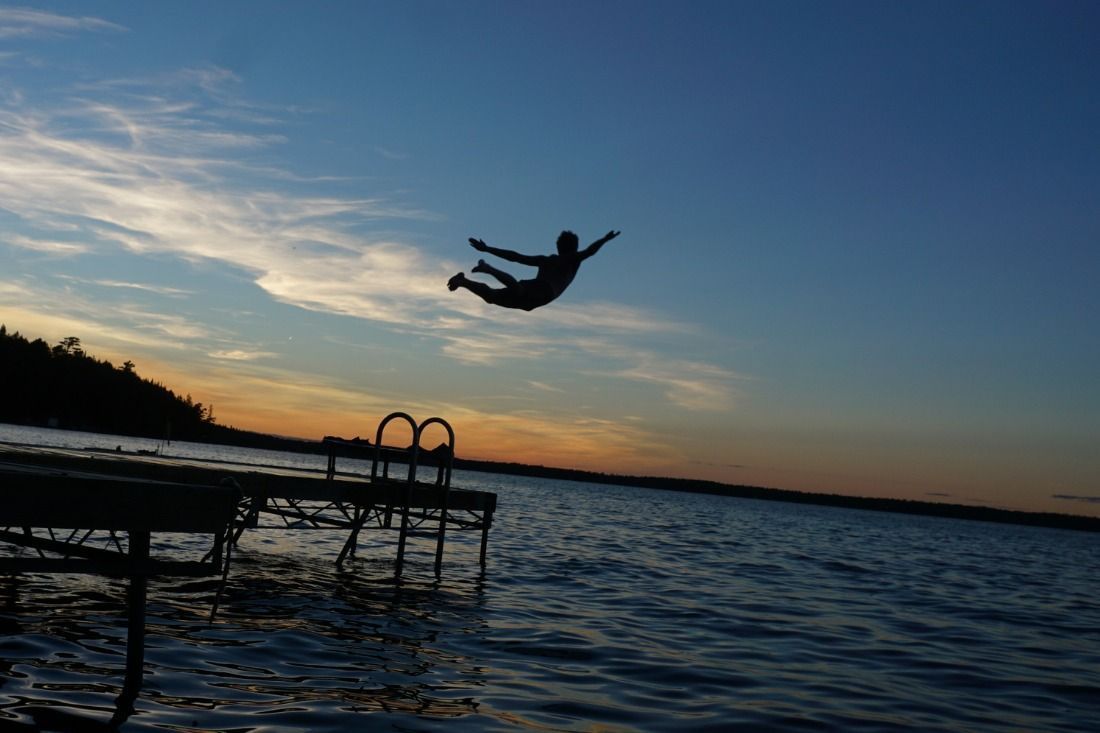 A Person is Jumping Into the Water From a Dock at Sunset — MoneySmith Group In Kingscliff, NSW