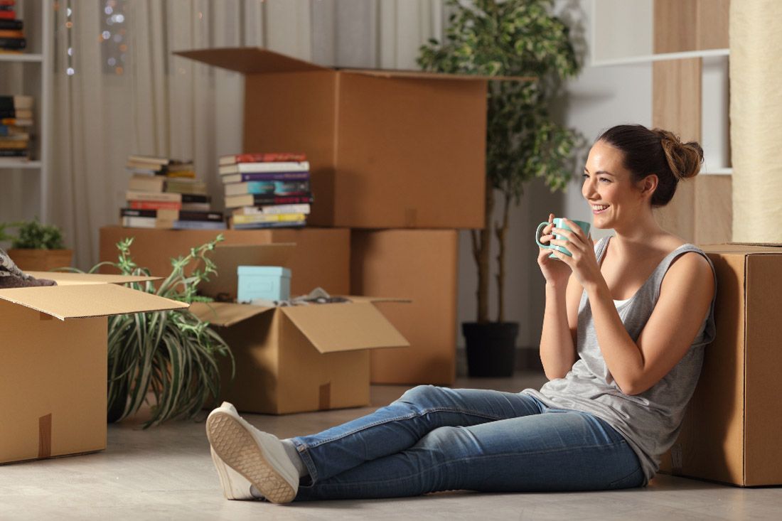 A Woman is Sitting on the Floor Drinking a Cup of Coffee — MoneySmith Group In Kingscliff, NSW