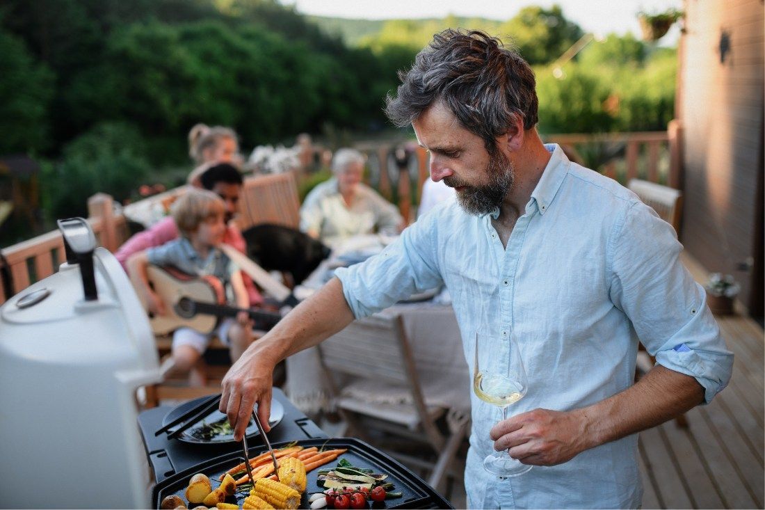 A Man Is Cooking Food On A Grill — MoneySmith Group In Kingscliff, NSW