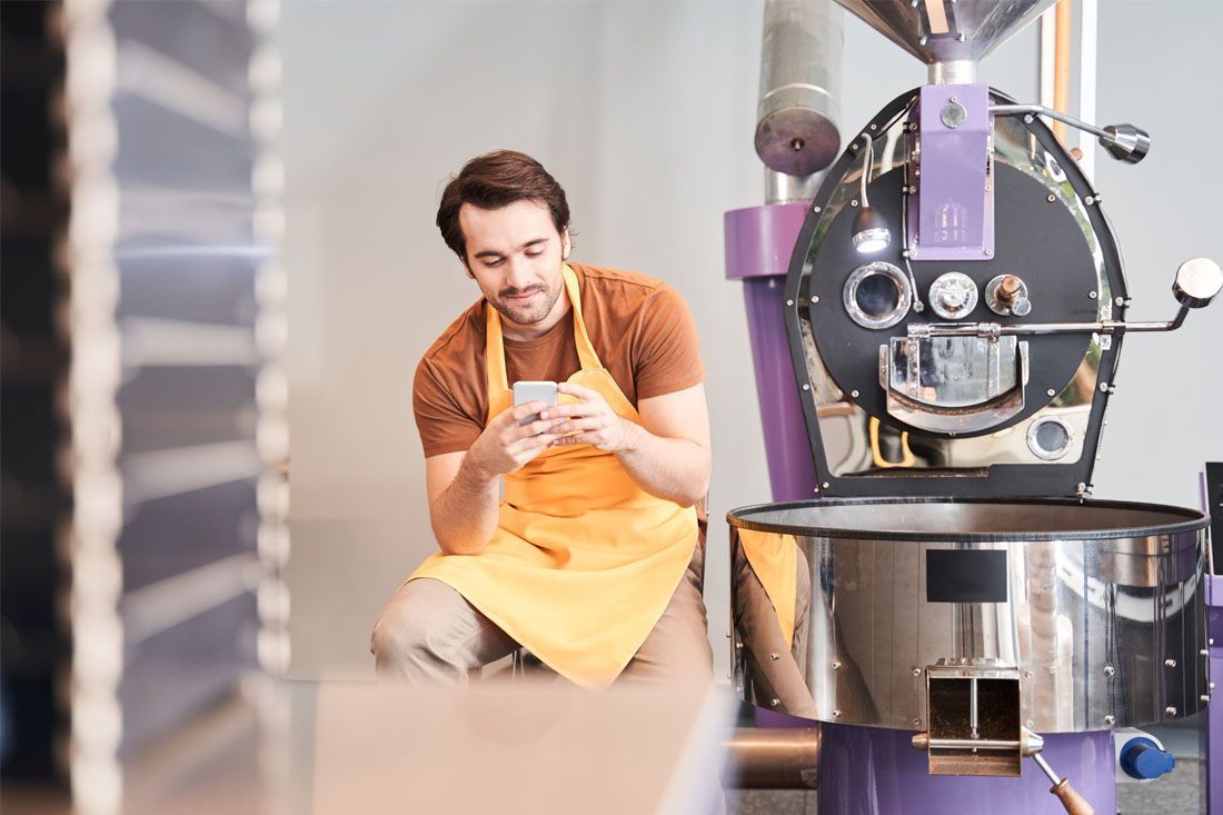 A Man is Sitting in Front of a Coffee Roaster — MoneySmith Group In Kingscliff, NSW