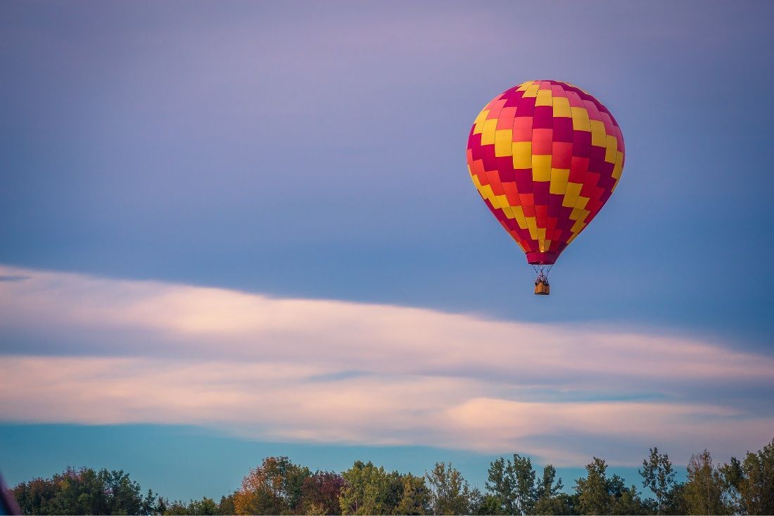 A Colorful Hot Air Balloon is Flying in the Sky Over a Field — MoneySmith Group In Kingscliff, NSW