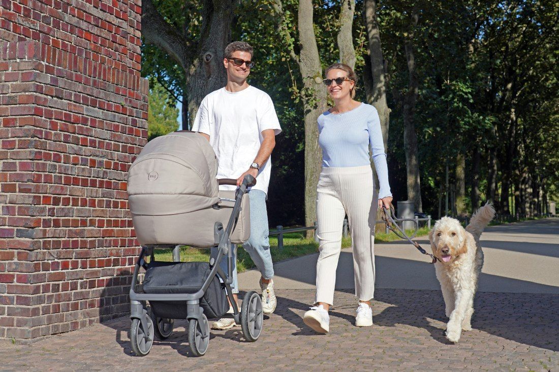 A Man and Woman Are Walking a Dog and Pushing a Stroller — MoneySmith Group In Kingscliff, NSW