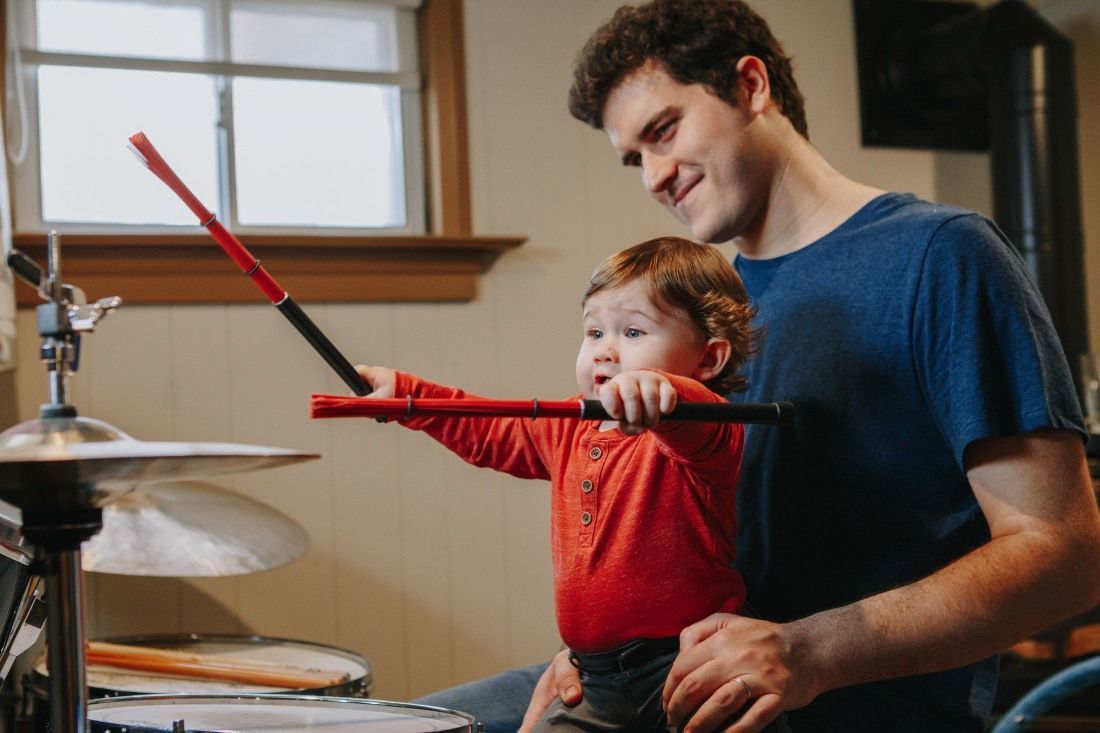 A Man and a Baby Are Playing Drums Together — MoneySmith Group In Kingscliff, NSW