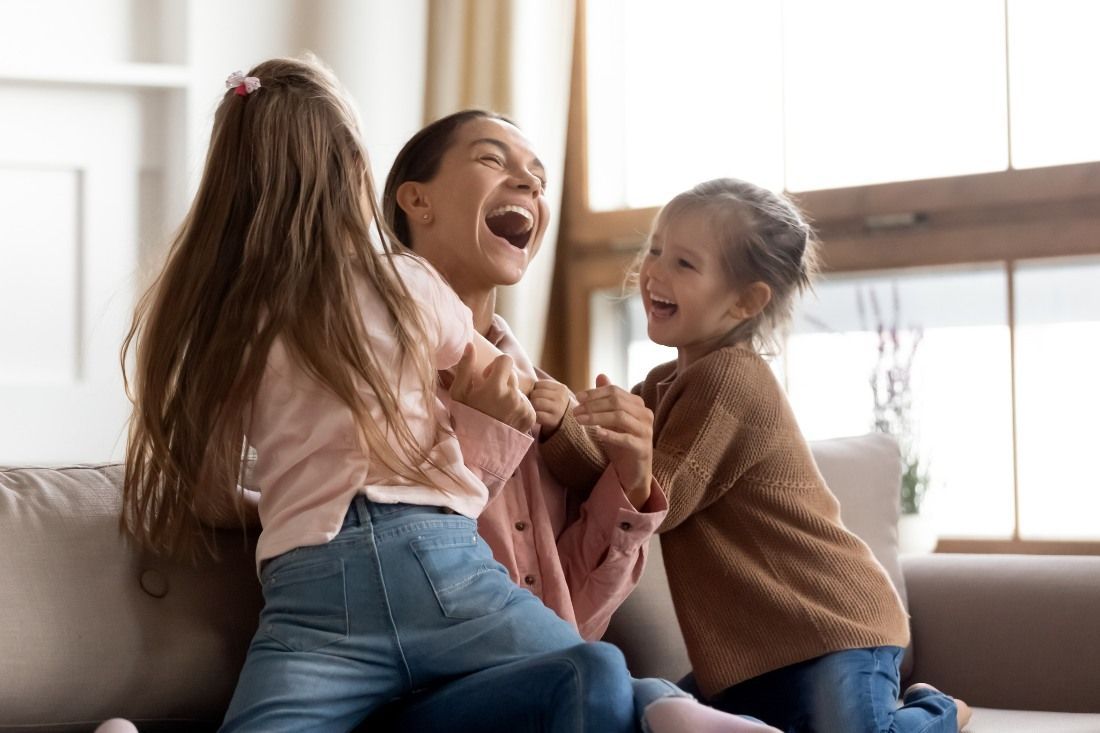 A Woman and Two Little Girls Are Playing on a Couch — MoneySmith Group In Kingscliff, NSW