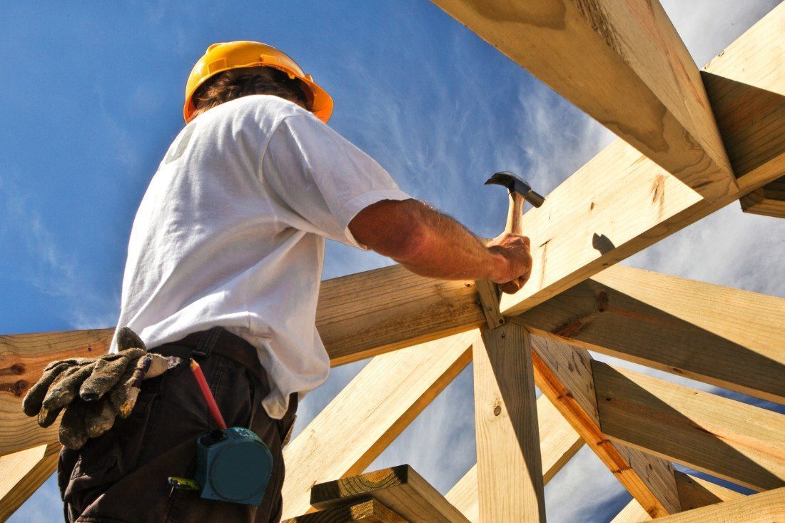 A Man Wearing A Hard Hat Is Hammering — MoneySmith Group In Kingscliff, NSW