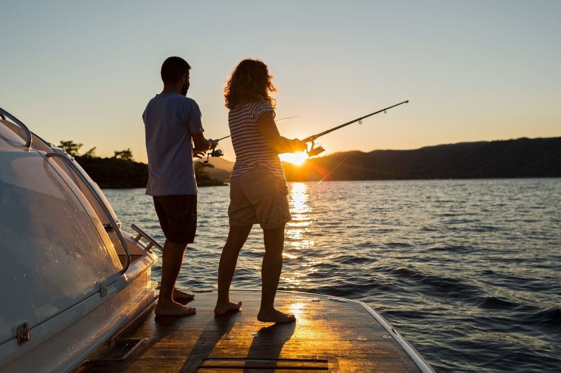 A Man and a Woman Are Fishing From a Boat at Sunset — MoneySmith Group In Kingscliff, NSW