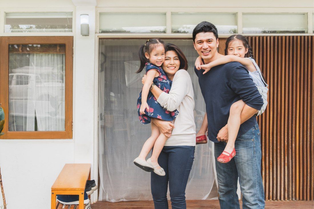 A Family is Posing for a Picture in Front of Their House — MoneySmith Group In Kingscliff, NSW