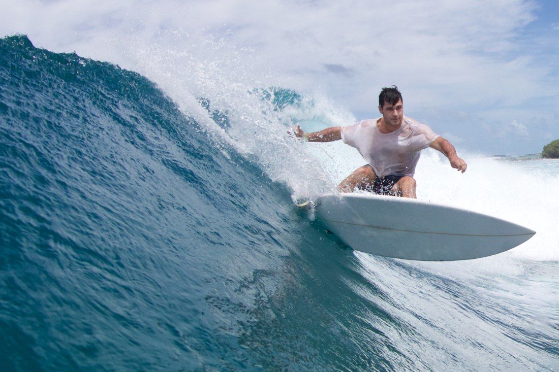 A Man Is Riding A Wave On A Surfboard — MoneySmith Group In Kingscliff, NSW
