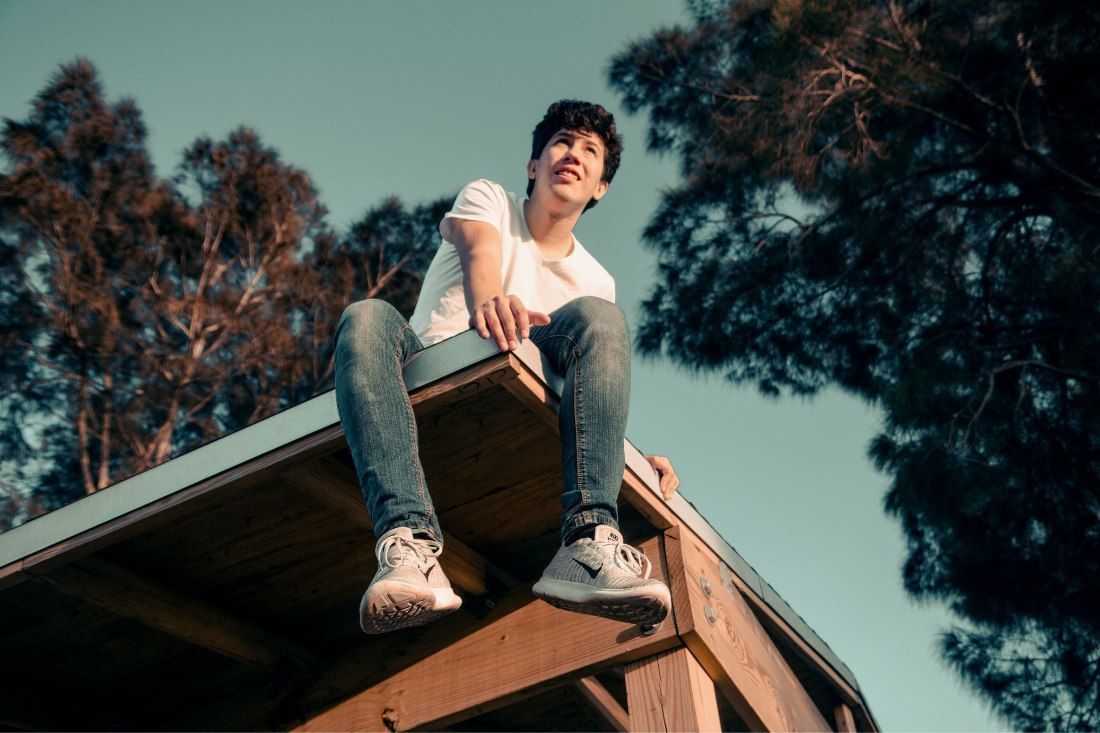 A Young Man is Sitting on the Roof of a Wooden Structure — MoneySmith Group In Kingscliff, NSW
