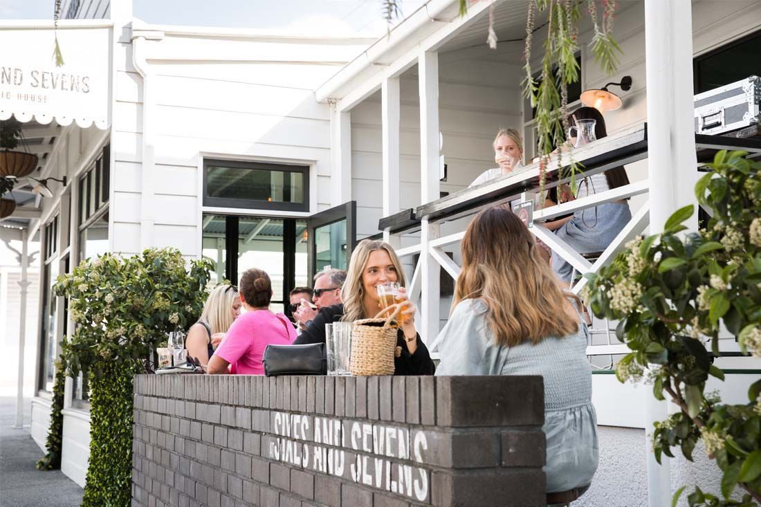 A Group of People Are Sitting Outside of a Restaurant — MoneySmith Group In Kingscliff, NSW