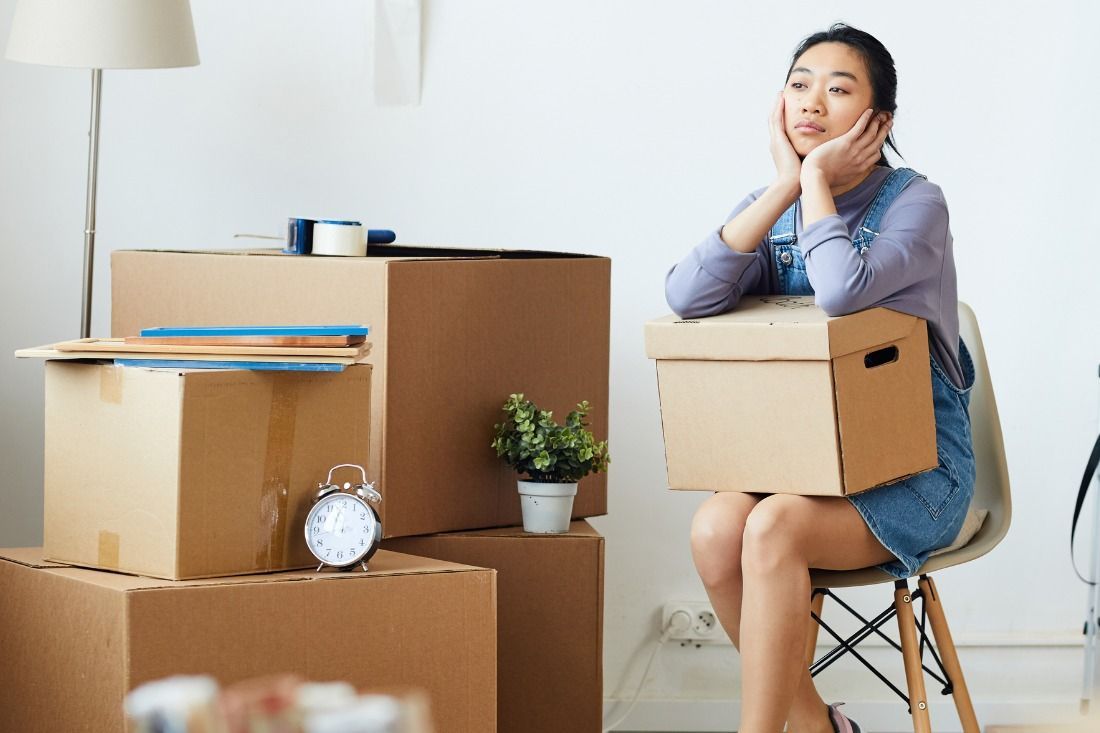 A Woman is Sitting in a Chair Holding a Cardboard Box — MoneySmith Group In Kingscliff, NSW