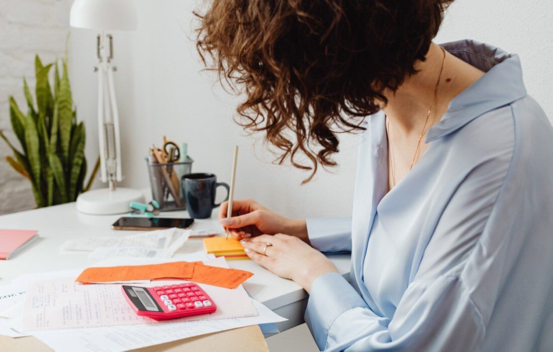 Woman is Sitting at a Desk With a Calculator — MoneySmith Group In Kingscliff, NSW