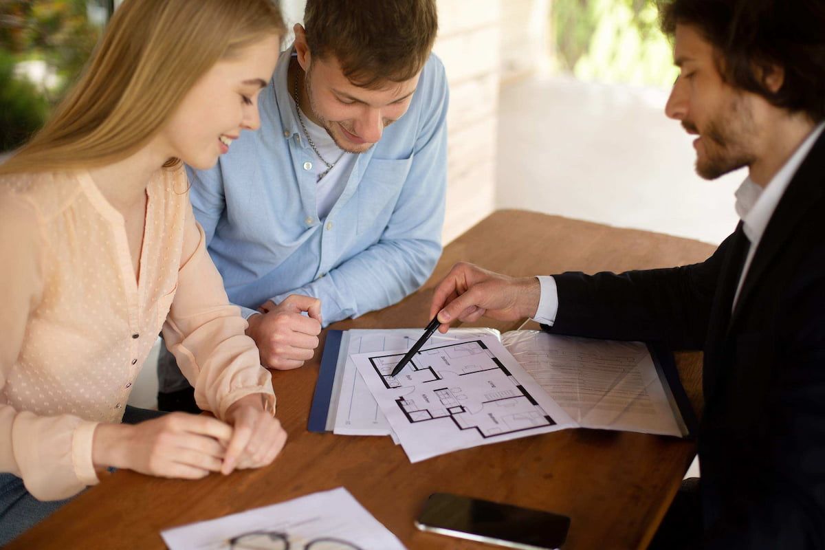 Three People Discussing Floor Plans at a Table, Pointing at Blueprints — MoneySmith Group In Kingscliff, NSW