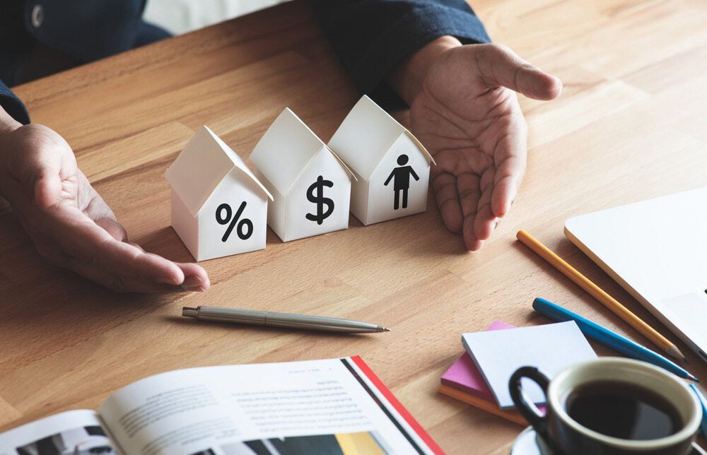 A Person is Holding a Model House With a Dollar Sign on It — MoneySmith Group In Northern Rivers, NSW