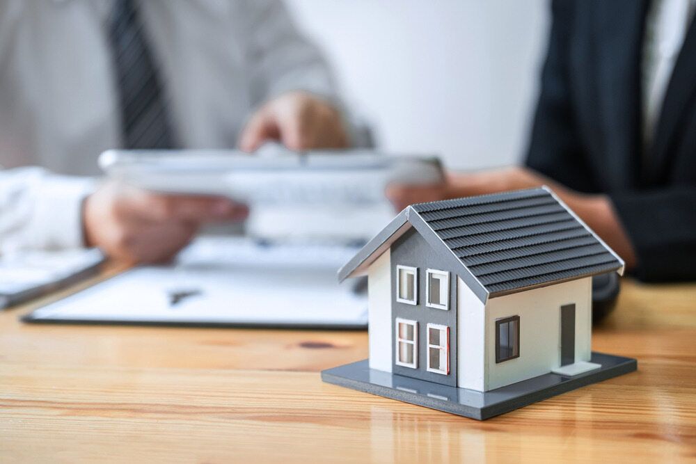 A Small Model House is Sitting on a Wooden Table — MoneySmith Group In Pottsville, NSW