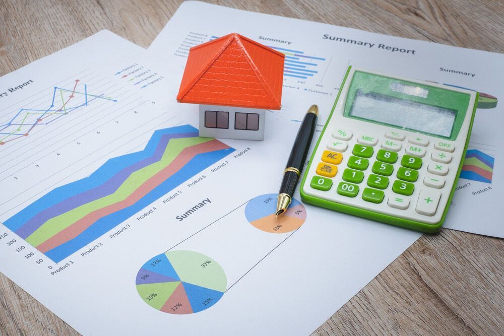 A Model House is Sitting on Top of a Table Next to a Calculator and a Pen — MoneySmith Group In Gold Coast, QLD