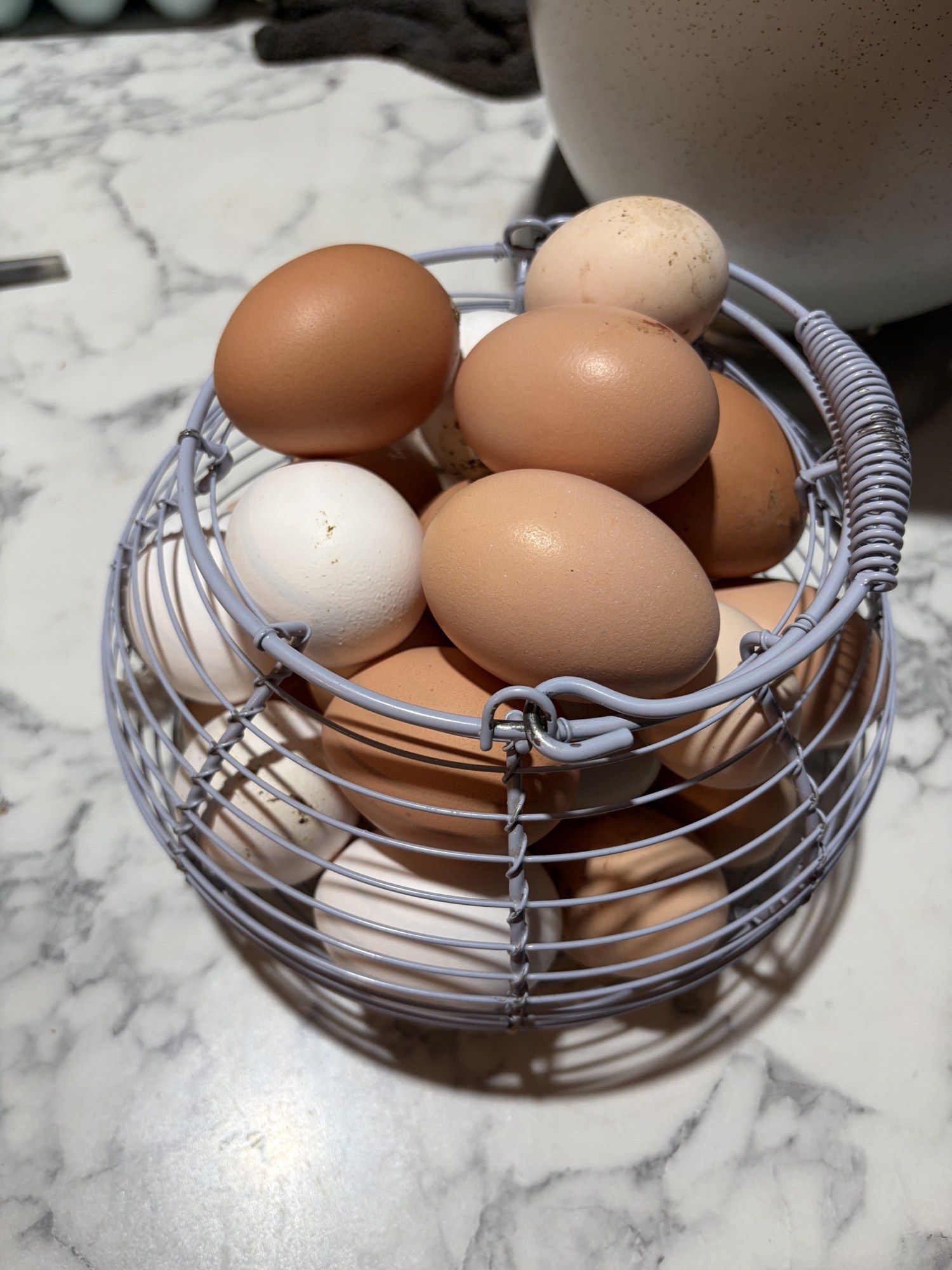 A wire basket filled with brown and white eggs from our flock