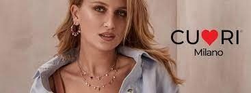 Donna che indossa gioielli e indossa una camicia chiara; logo CUORI Milano sulla destra.