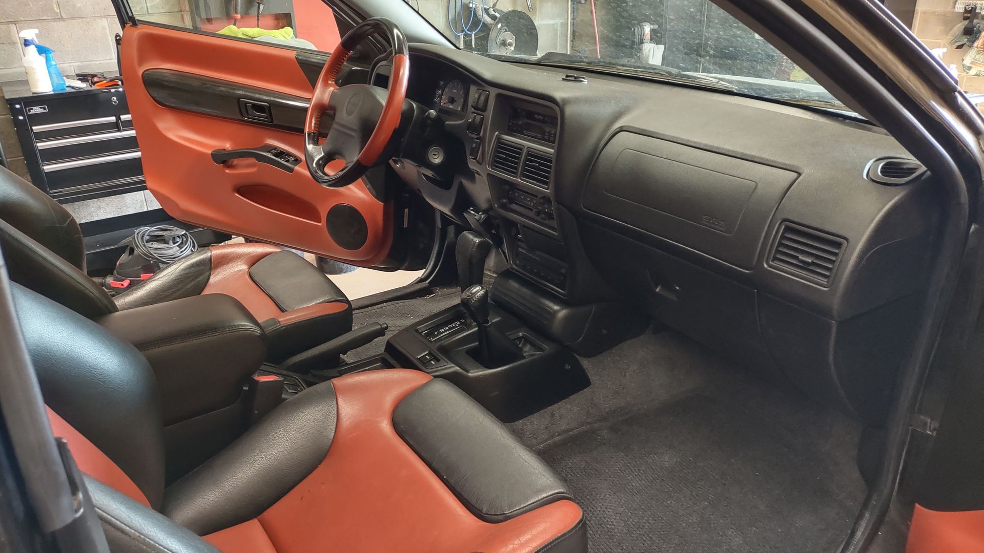 The interior of a car with red and black seats and a steering wheel.
