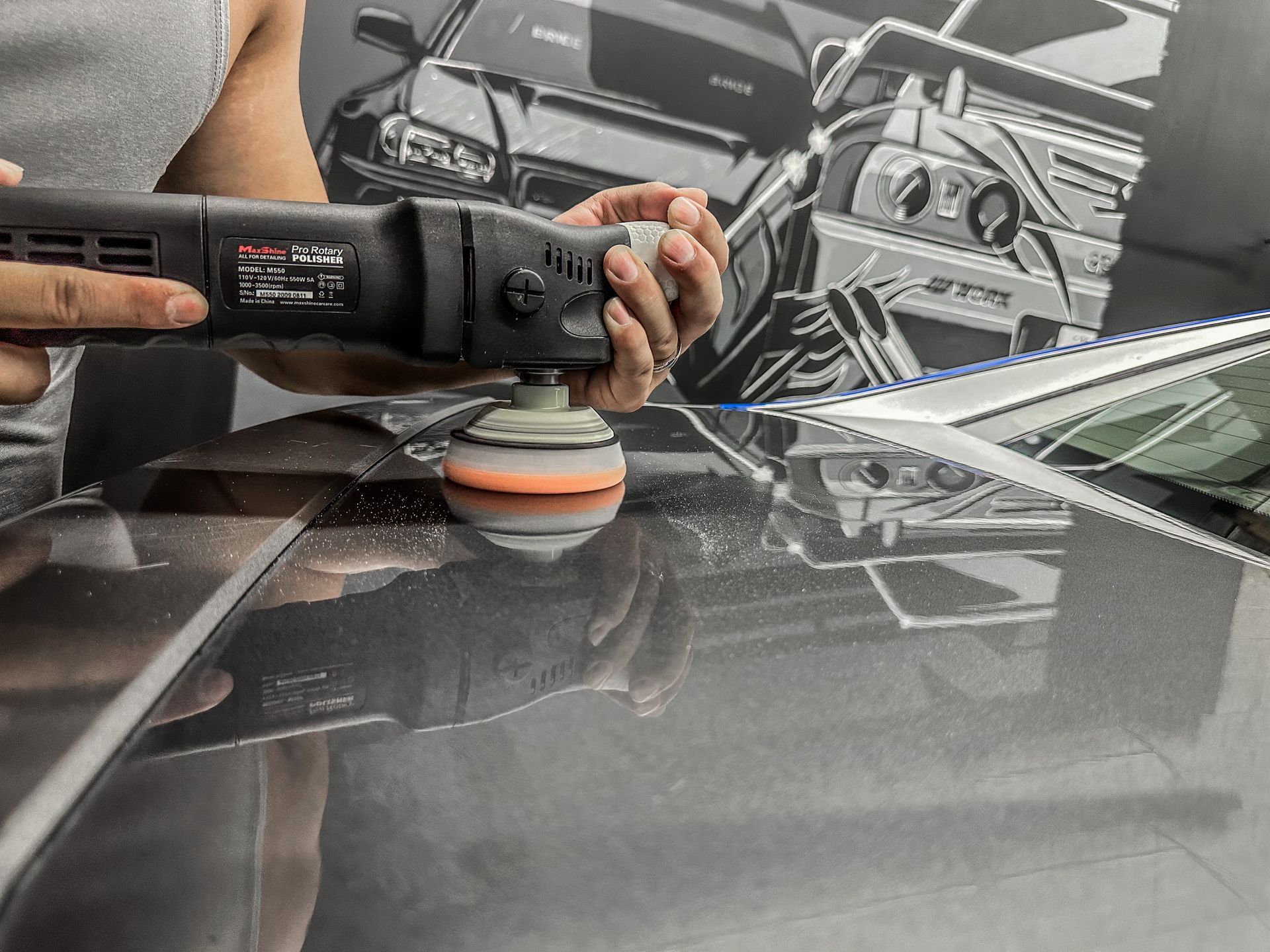 A person is polishing a car with a machine.