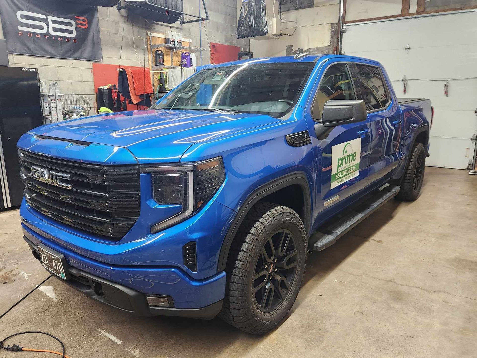 Blue pickup truck in a garage, shown from the front-left side with black wheels.