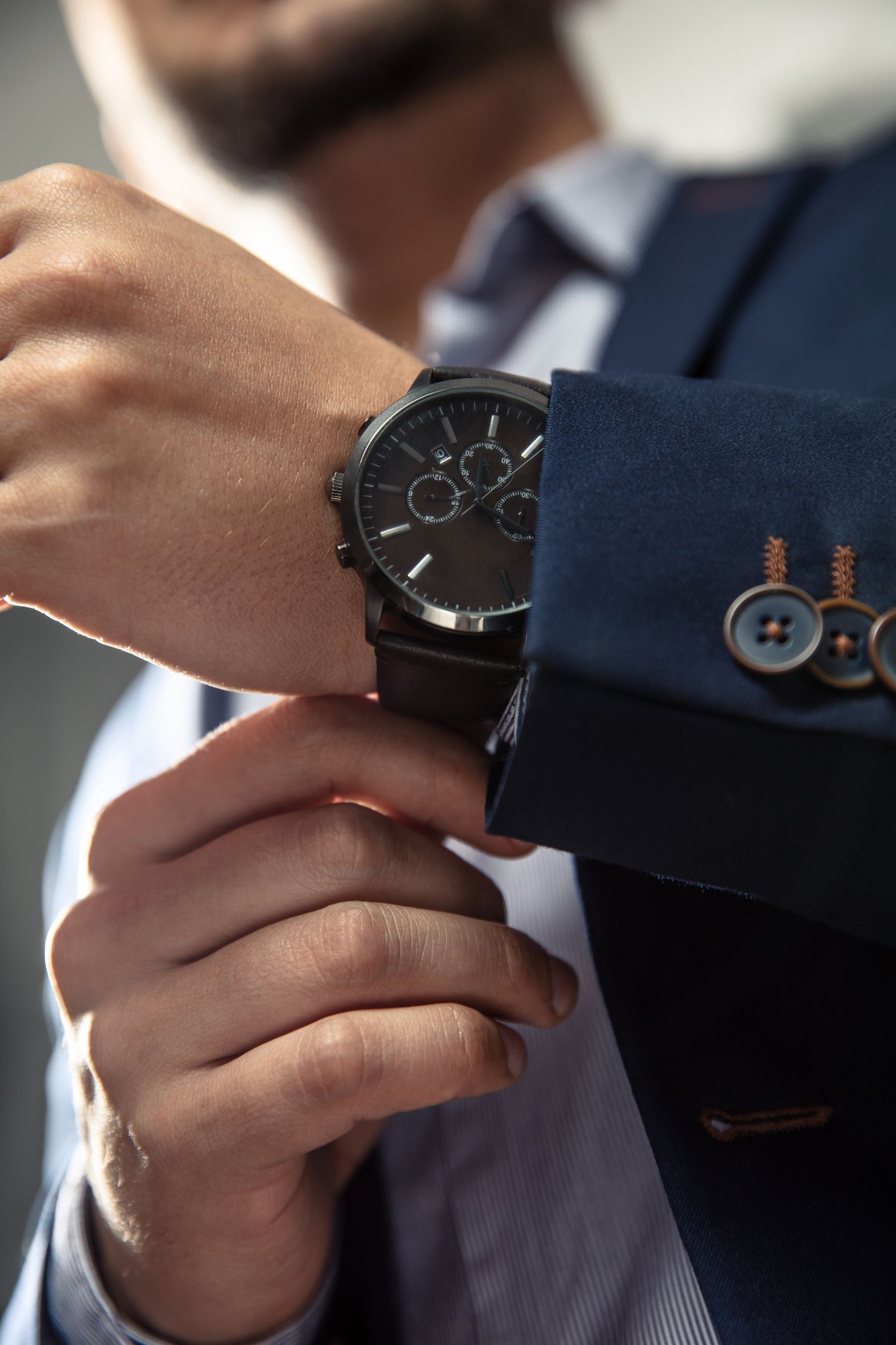 Uomo che sistema l'orologio al polso, indossando un blazer blu.