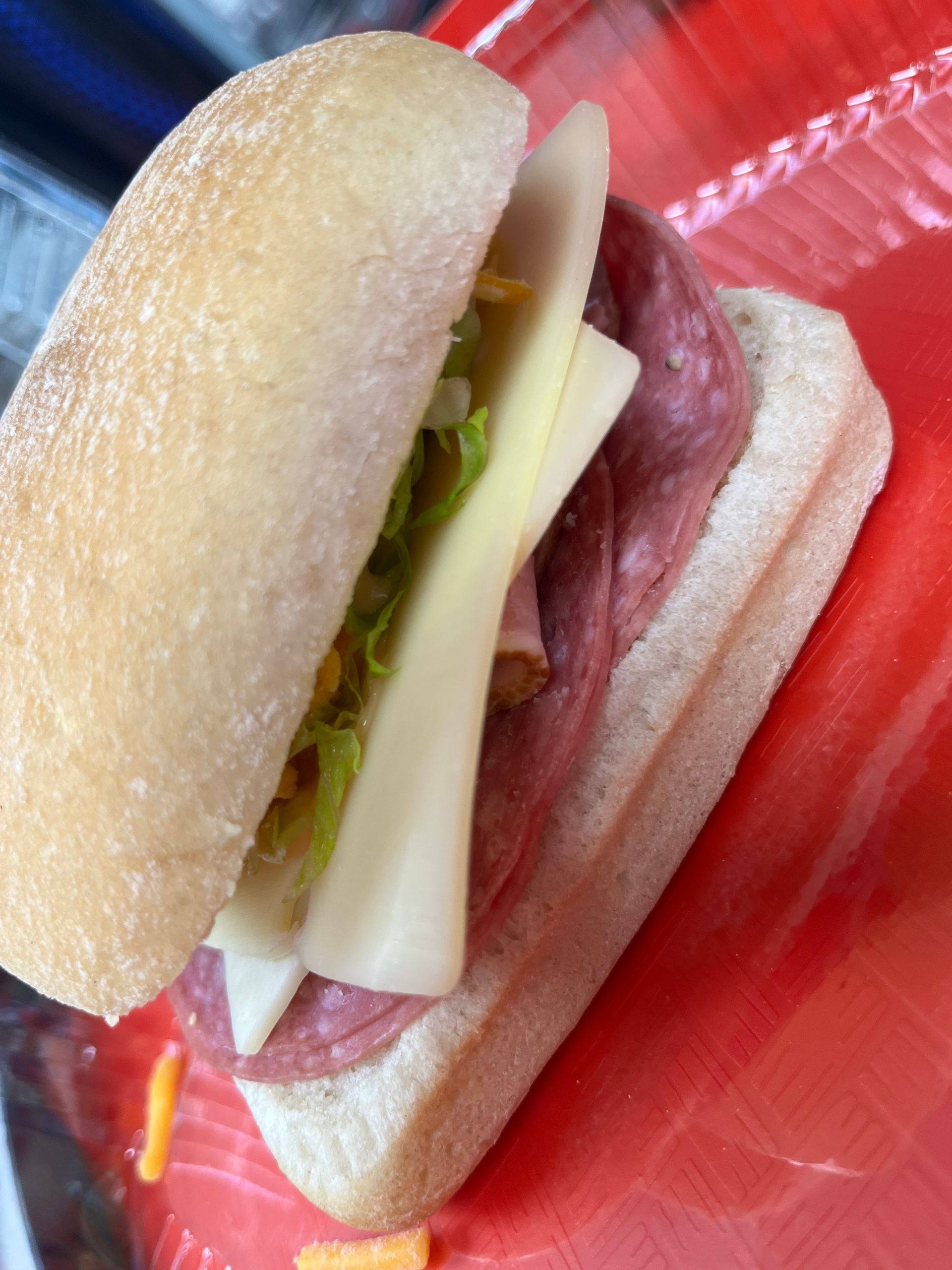 Hot dog in a bun with mustard and relish on a red tray
