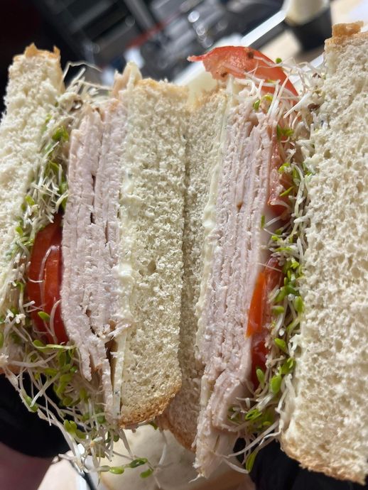 Close-up of a triangular club sandwich with turkey, tomato, lettuce, and toothpicks on a black plate