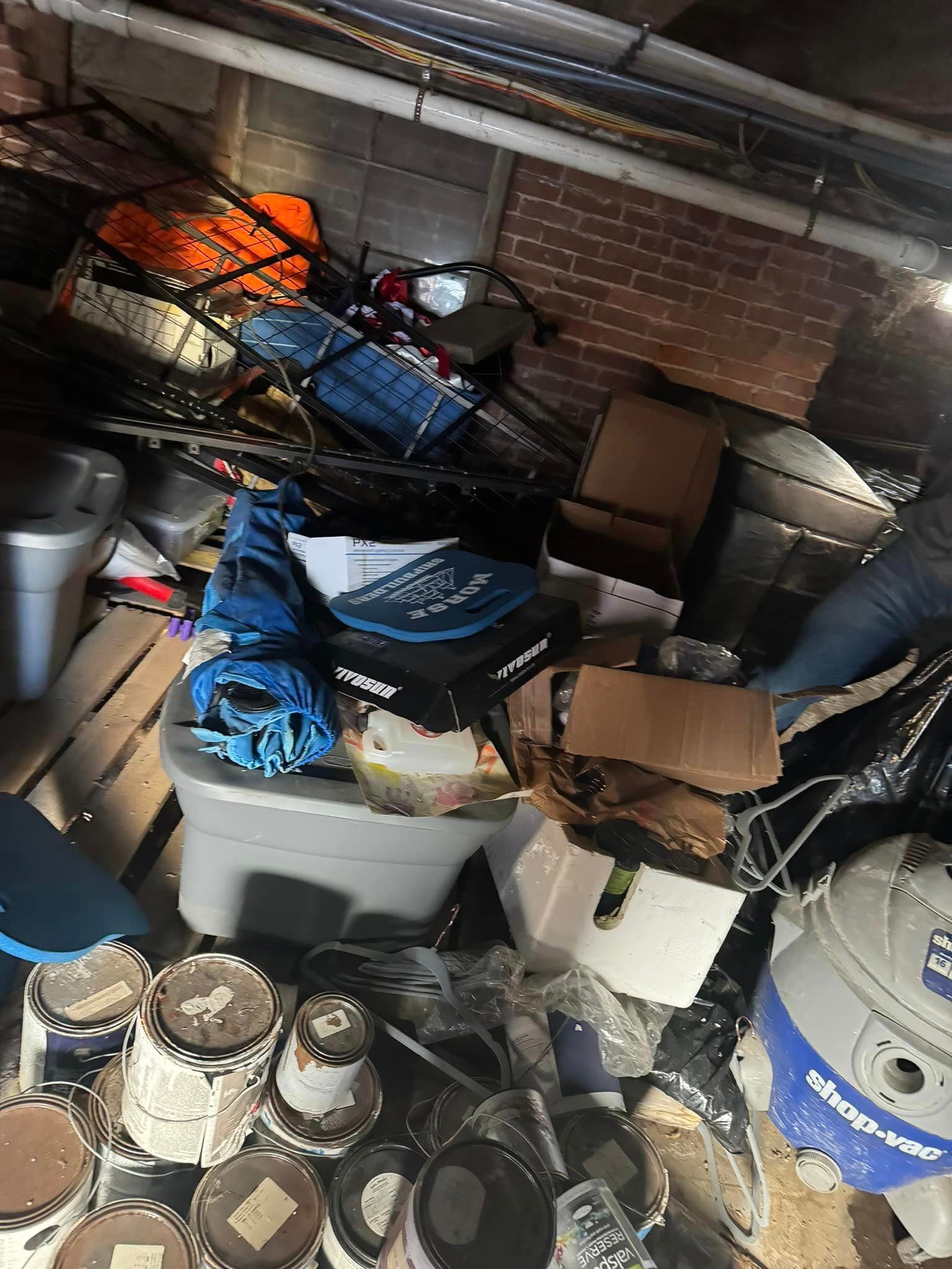 A garage filled with lots of junk and a vacuum cleaner.