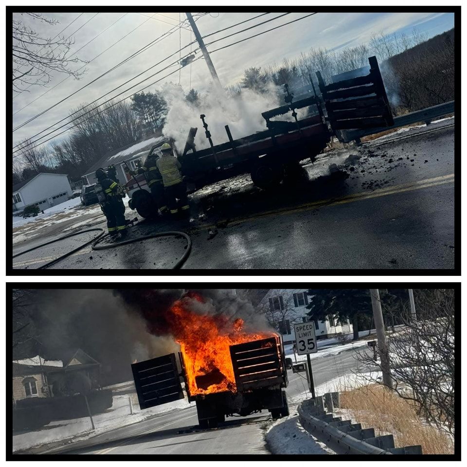 Overturned truck burning on a snowy roadside, with flames and smoke near a neighborhood street.